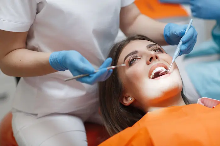 بهترین روکش دندان چیست؟، نمایی از صورت فردی درحال کشیدن دندان توسط دندان پزشک 