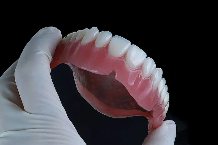 نصویری از فک بالای دندان مصنوعی در دستان فرد 